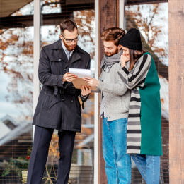 Real estate agent looking over paperwork with couple outside of a home
