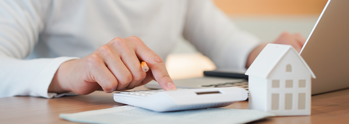 Man in front of laptop using a calculator off to the side