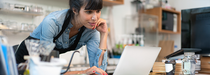 Woman leaning over her laptop in a coffee talk or cafe